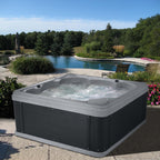 Hot tub with water features in a garden setting with trees and flowers.