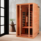 Wooden sauna with a small table and plant in a room with large windows.