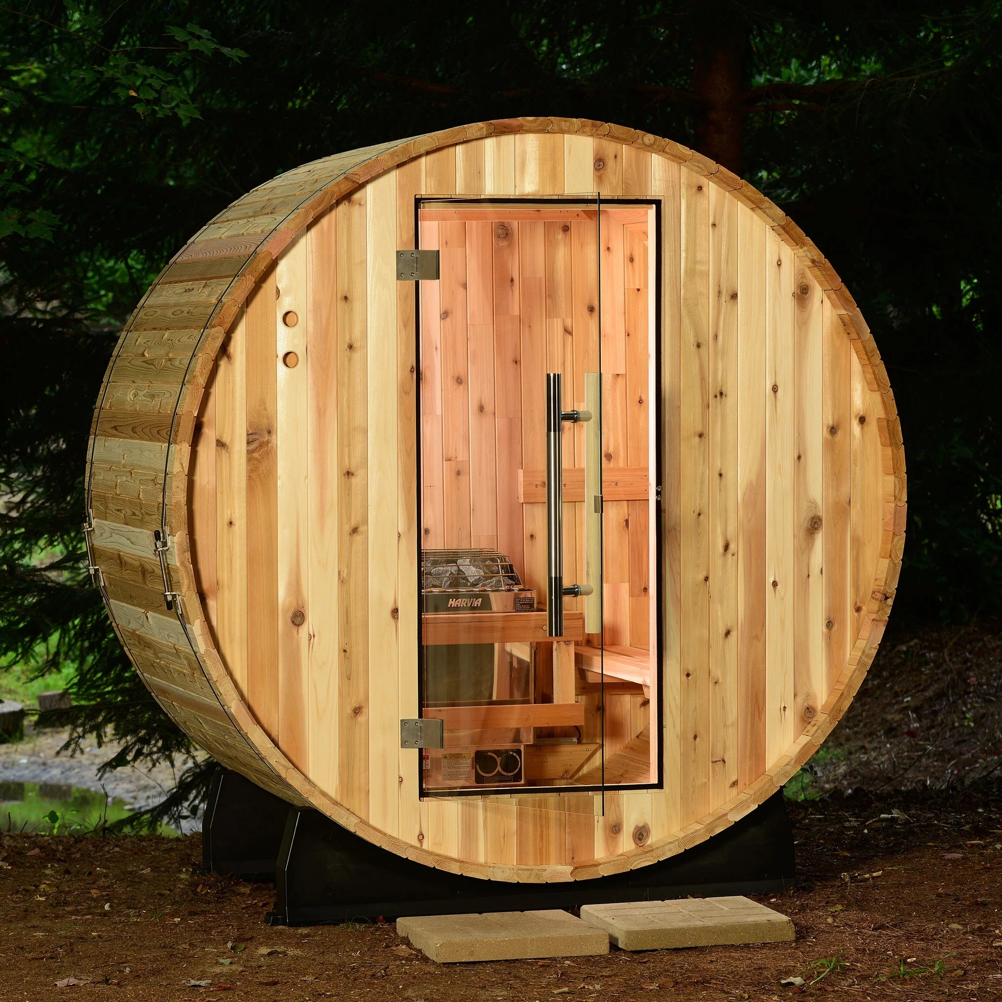Wooden barrel-shaped sauna in a forest setting.