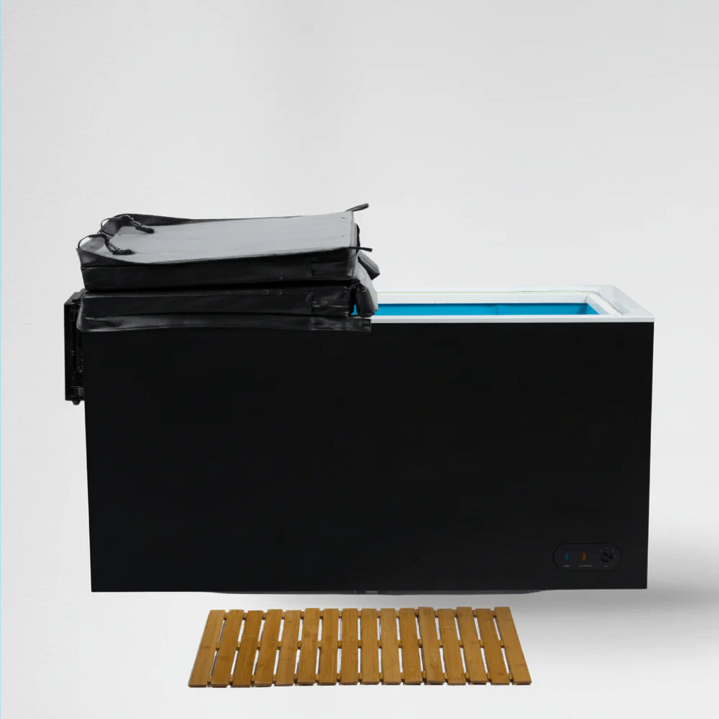 Black cold plunge with cover and a wooden mat on a white background.