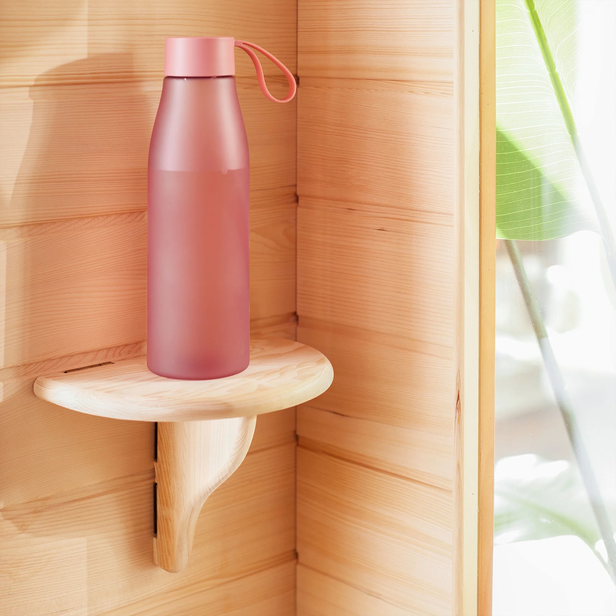 Pink water bottle on a wooden shelf with a blurred background.
