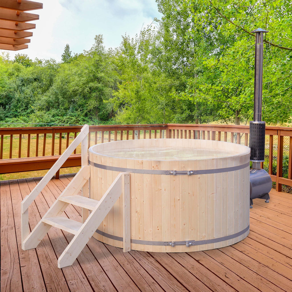Wooden hot tub on a wooden deck with trees in the background.