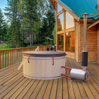 Wooden hot tub on a wooden deck with a cabin in the background.